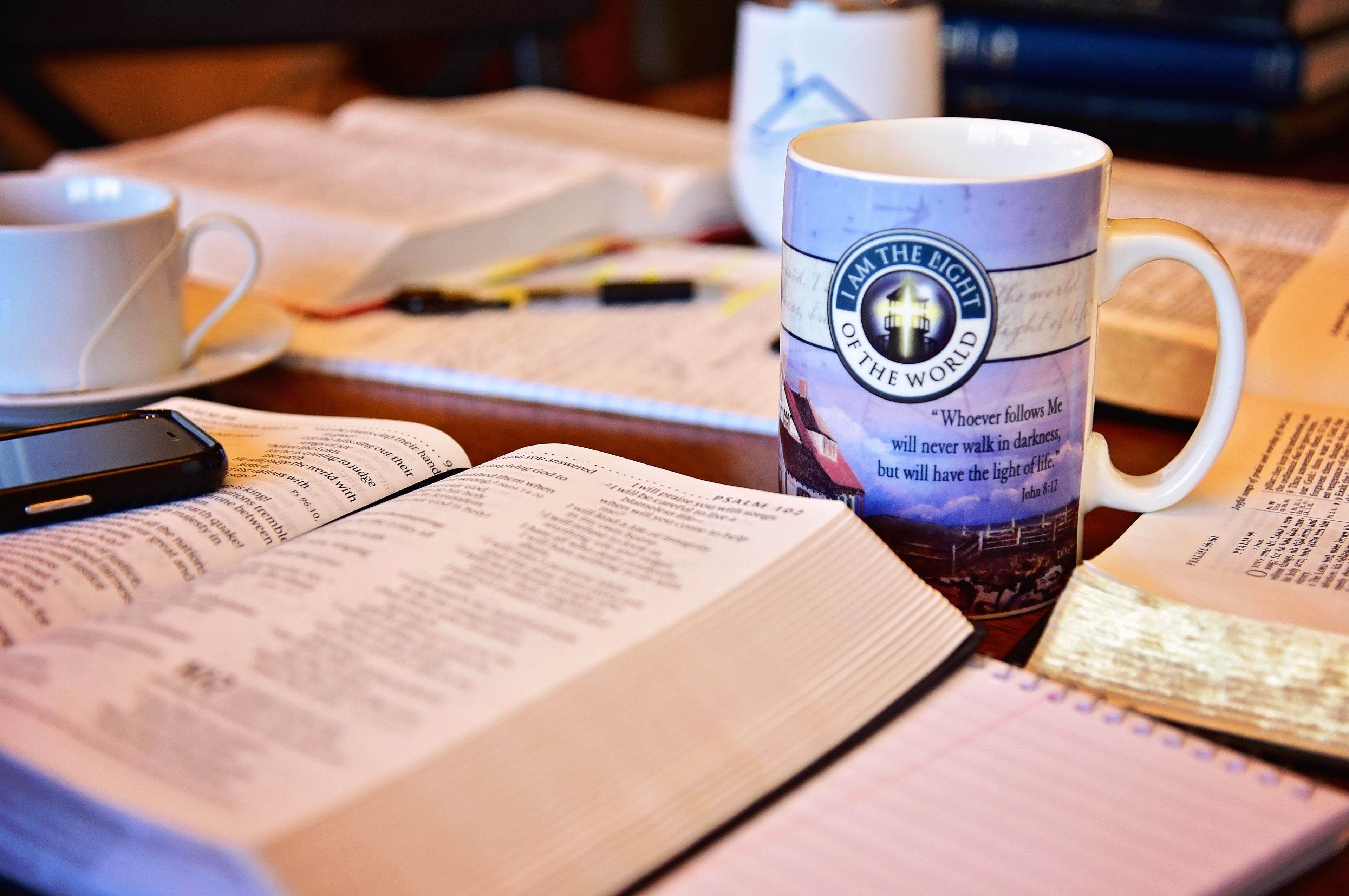 Bible and study materials with a religious-themed candle on a desk.